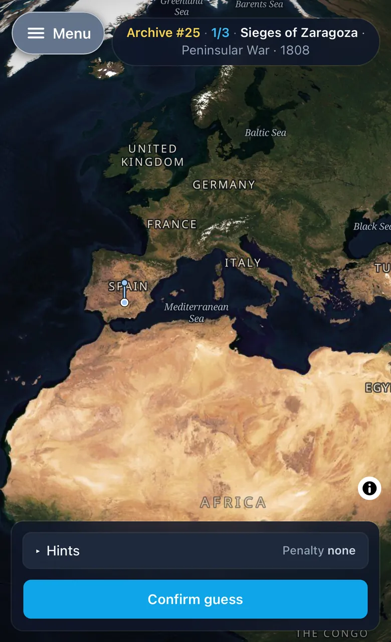 A round in progress on a phone. A one-line header gives the battle, its war and its year, and the satellite globe below shows Europe and North Africa with a blue guess pin dropped in Spain. At the bottom sit a collapsed Hints control reading Penalty none and a Confirm guess button.